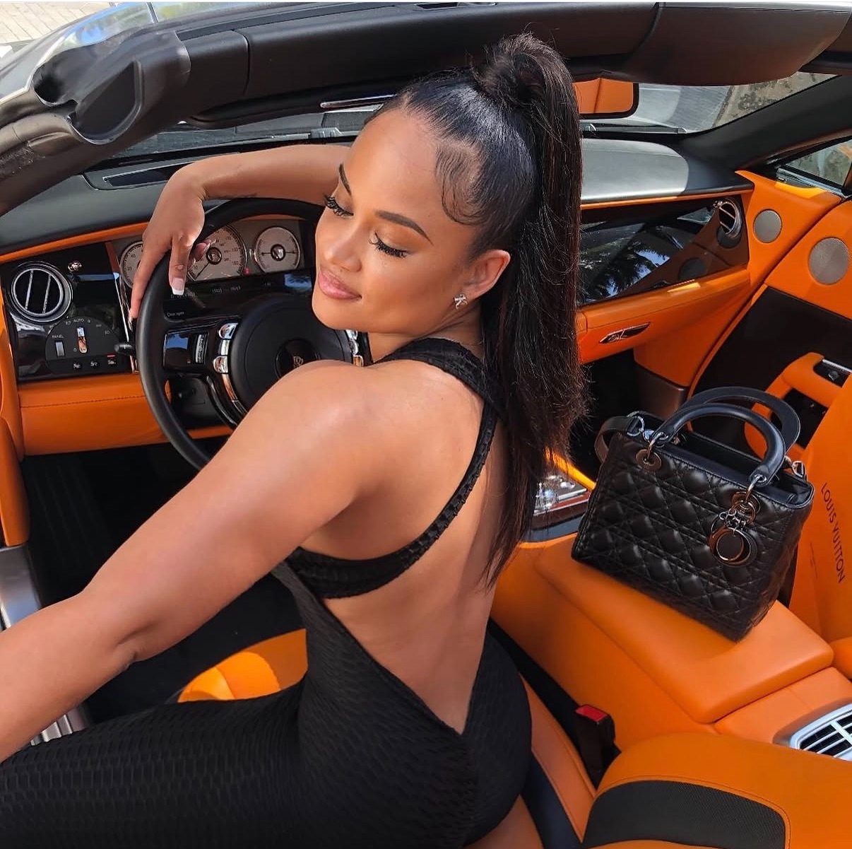 Woman in the driver's seat of an orange luxury convertible